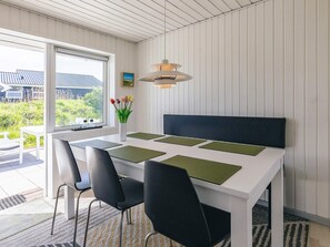 A modern dining area with a white table, black chairs, and a pendant light.