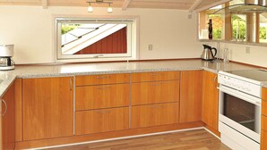 A kitchen with wooden cabinets, a built-in oven, and a window with a view of the roof.