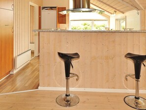 Een keuken met houten kastjes, een roestvrijstalen afzuigkap en twee barkrukken.