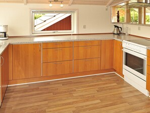 Une cuisine avec des meubles de rangement en bois, un four encastré et une fenêtre donnant sur le toit.