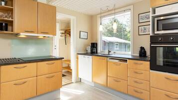 A modern kitchen with wooden cabinets, a black countertop, a microwave, and an oven.