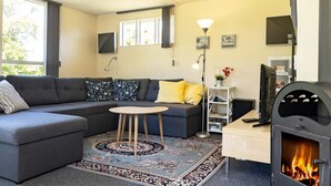 A modern living room with a sectional sofa, a small round table, a fireplace, and a television.