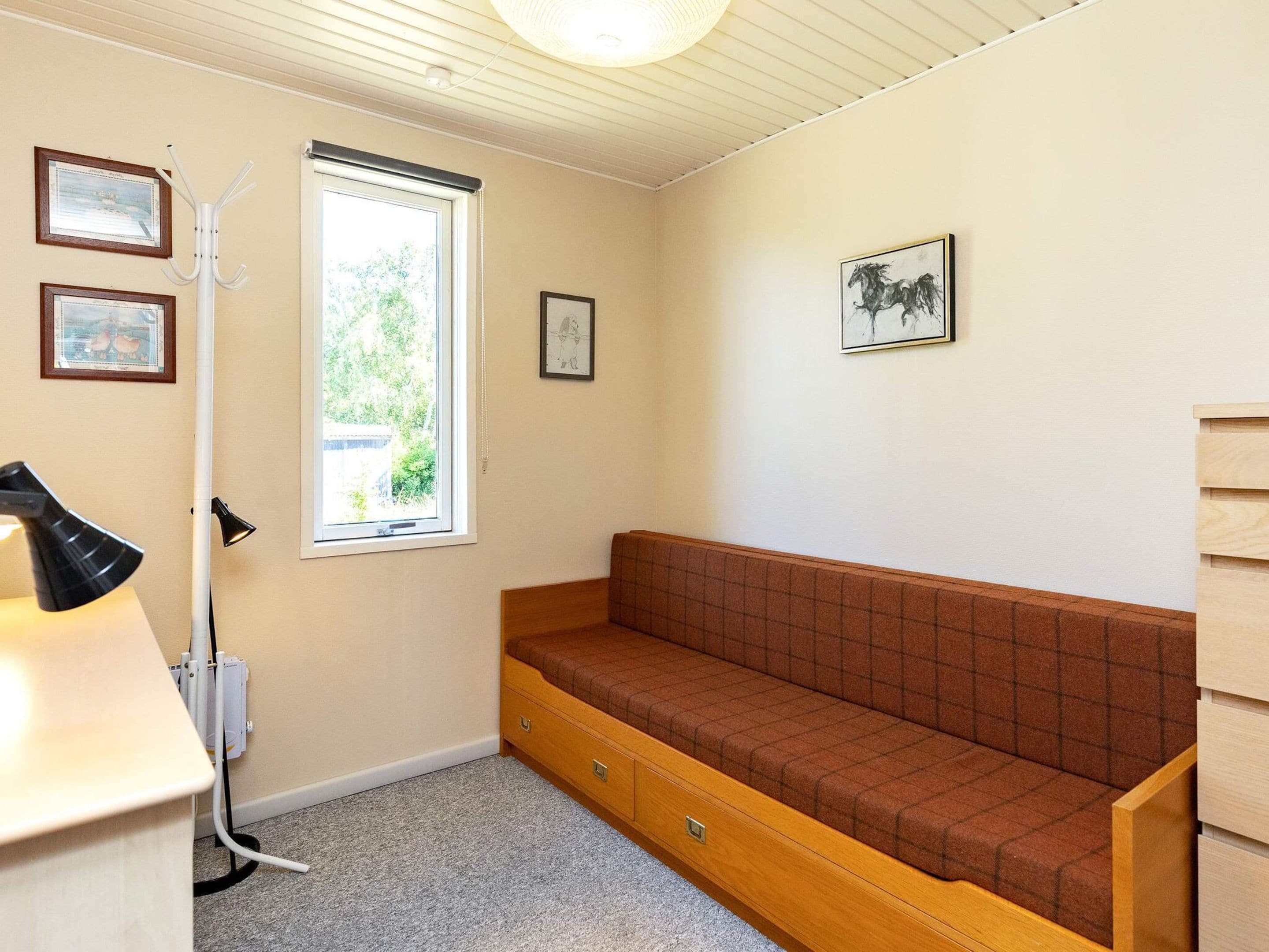 Et lille rum med en træbænk, en radiator, et vindue og billeder i rammer på væggen.
