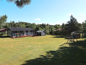 A residential property with a house, a covered patio, and a swing set in a grassy yard. - 4 Star Holiday Home in Nibe (Nibe)