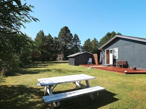 A picnic table in a grassy area with a shed and a building with a door in the background.