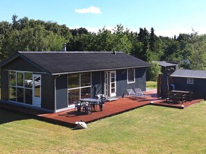 A modern house with a large deck, a covered patio, and a small adjacent shed. - 4 Star Holiday Home in Nibe (Nibe)