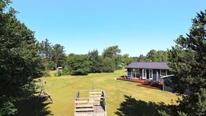 A house with a deck and a fenced area with a wooden structure.