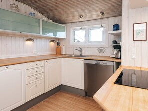 A kitchen with wooden cabinets, a dishwasher, and a window.