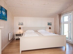 A bedroom with a wooden ceiling, two bedside tables with lamps, a bed with white bedding, and a window with curtains. - 4 Person Holiday Home in Ringkobing (Ringkobing)