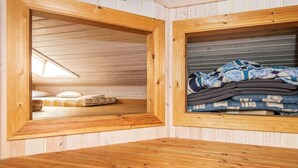 A wooden interior with a loft bed and a storage area with folded blankets. - Inviting Holiday Home in Ebeltoft near Sea (Ebeltoft)