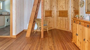 A wooden interior with a slanted ceiling, a wicker chair, and a wooden cabinet with drawers. - Inviting Holiday Home in Ebeltoft near Sea (Ebeltoft)