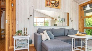 A cozy living room with a grey sectional sofa, a small white side table, and a round white table. - Inviting Holiday Home in Ebeltoft near Sea (Ebeltoft)