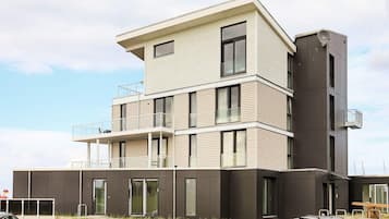 A multi-story building with a flat roof, large windows, and a balcony on the upper floor.