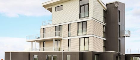 Un immeuble à plusieurs étages, doté d’un toit plat, de grandes fenêtres et d’un balcon situé à l’étage supérieur.