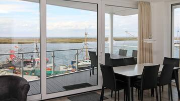Ein modernes Zimmer mit einer großen Schiebeglasdoor zum Balkon mit Blick auf das Wasser und Boote.