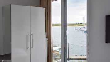 Ein Zimmer mit einem großen Fenster, einem Kleiderschrank und einem Bett.
