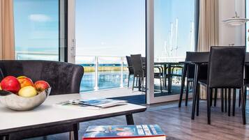 Ein Zimmer mit Essbereich, einem Tisch mit Obstschale und Meerblick.