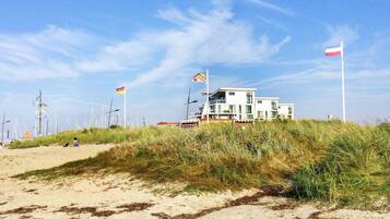 Ein Küstengebäude mit mehreren Flaggen, umgeben von Sand und Gras.