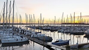 A marina with multiple boats docked, a wooden dock, and calm water reflecting the boats. - Holiday Home in Wendtorf (Schönberg)