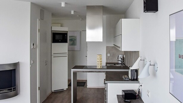 A compact kitchen with a microwave, oven, and coffee maker. There's a small dining area with a table and chairs. - Holiday Home in Wendtorf (Schönberg)