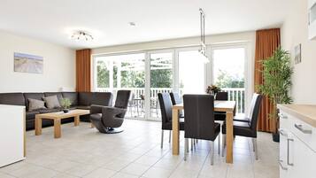 A modern living room with a sofa, coffee table, and dining area with chairs and a table.