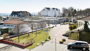 A parking area with a car, a building with a sloped roof, and a clear sky. - Holiday Home in Grossenbrode (Grossenbrode)