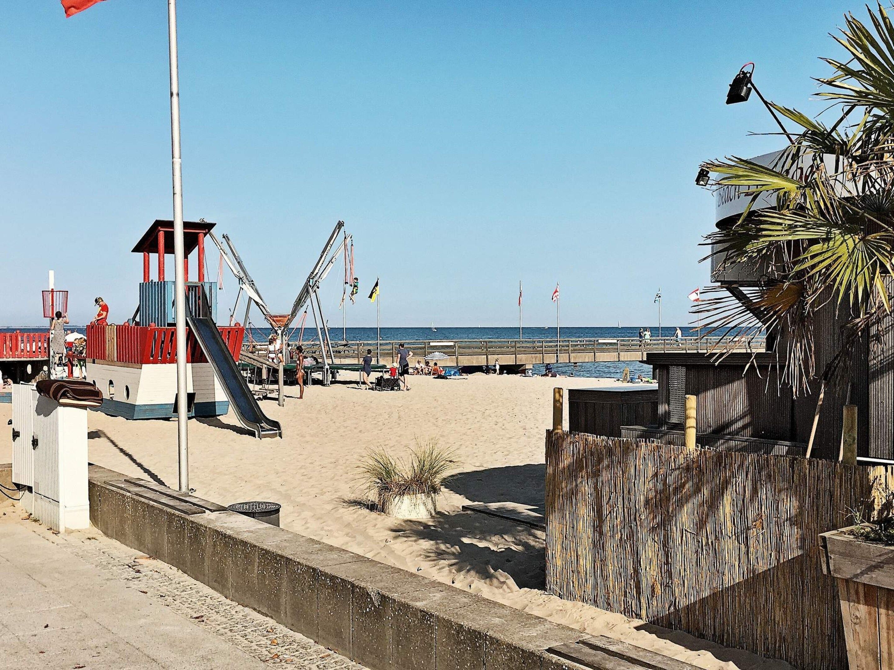 Una playa con una torre de salvavidas, un área de juegos y una valla de madera.