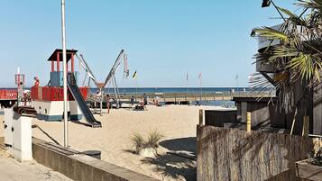 A beach with a lifeguard tower, a playground, and a wooden fence.