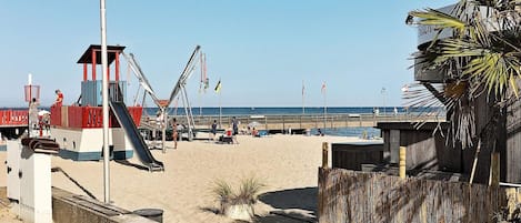 Una playa con una torre de salvavidas, un área de juegos y una valla de madera.