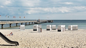 A beach with a pier, beach chairs, and a slide. - Holiday Home in Grossenbrode (Grossenbrode)