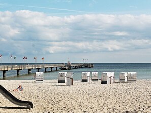 A beach with a pier, beach chairs, and a slide. - Holiday Home in Grossenbrode (Grossenbrode)