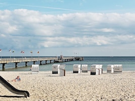 Una playa con un muelle, sillas de playa y un tobogán.