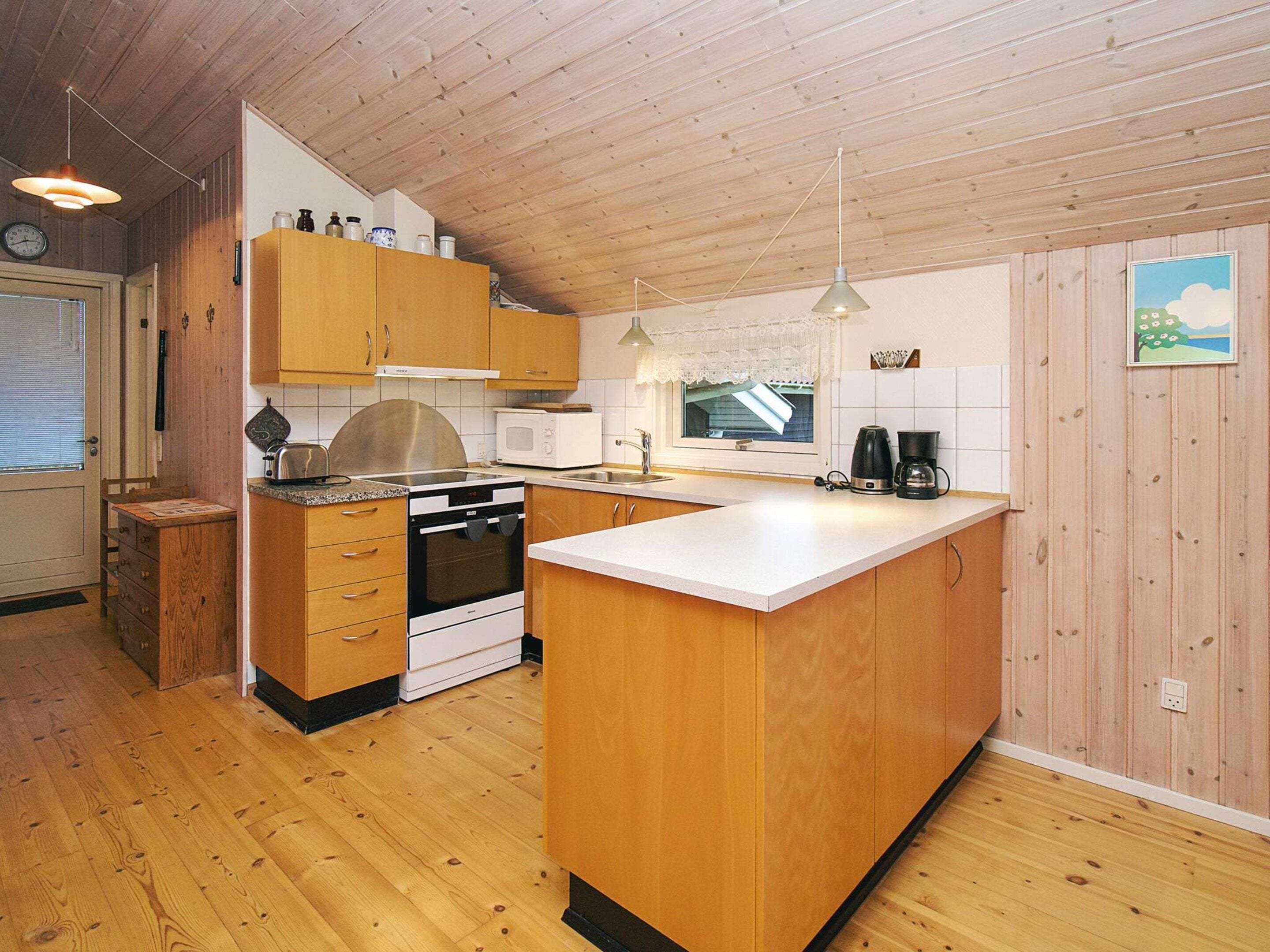 A compact kitchen with wooden cabinets, a stove, a microwave, and a coffee maker.