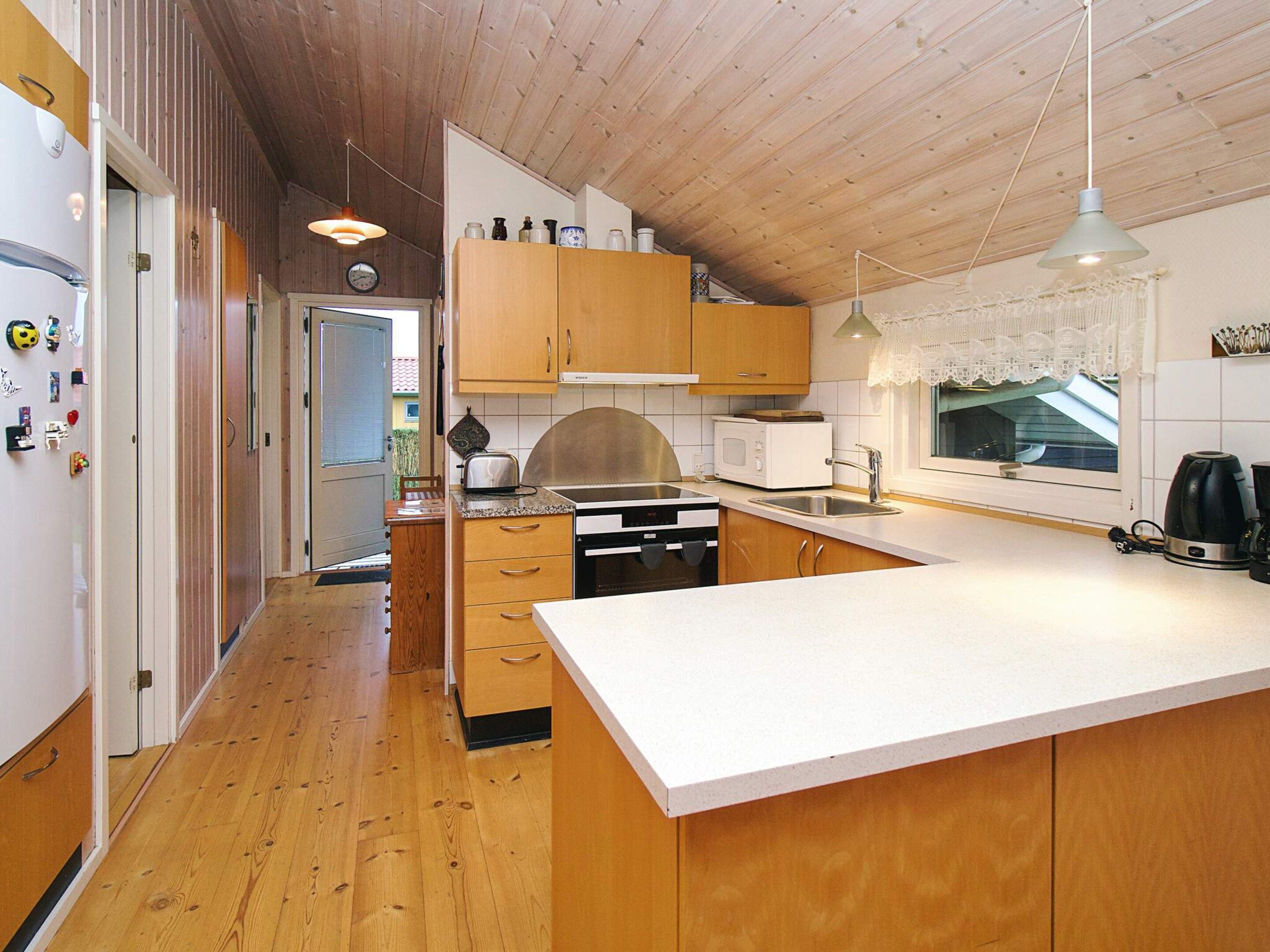 Una cocina moderna con armarios de madera, una isla grande, un microondas y un hervidor.