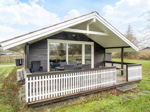 A modern house with a covered porch, large sliding glass doors, and outdoor seating. - 6 Person Holiday Home in Skibby (Skibby)