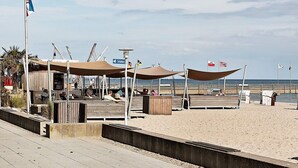 Un molo sulla spiaggia con una passerella in legno, zone d'ombra e vista sull'oceano.