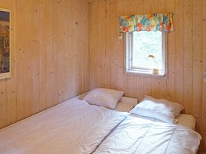 A single bed with white bedding in a room with wooden walls and a window with a floral valance. - 4 Person Holiday Home in Ekero (Ekerö)