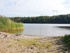 A natural landscape with a lake, a forested area, and power lines in the distance. - 4 Person Holiday Home in Ekero (Ekerö)