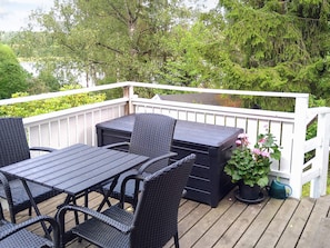 A deck with a table and chairs, surrounded by a white railing, and a potted plant with pink flowers. - 4 Person Holiday Home in Ekero (Ekerö)