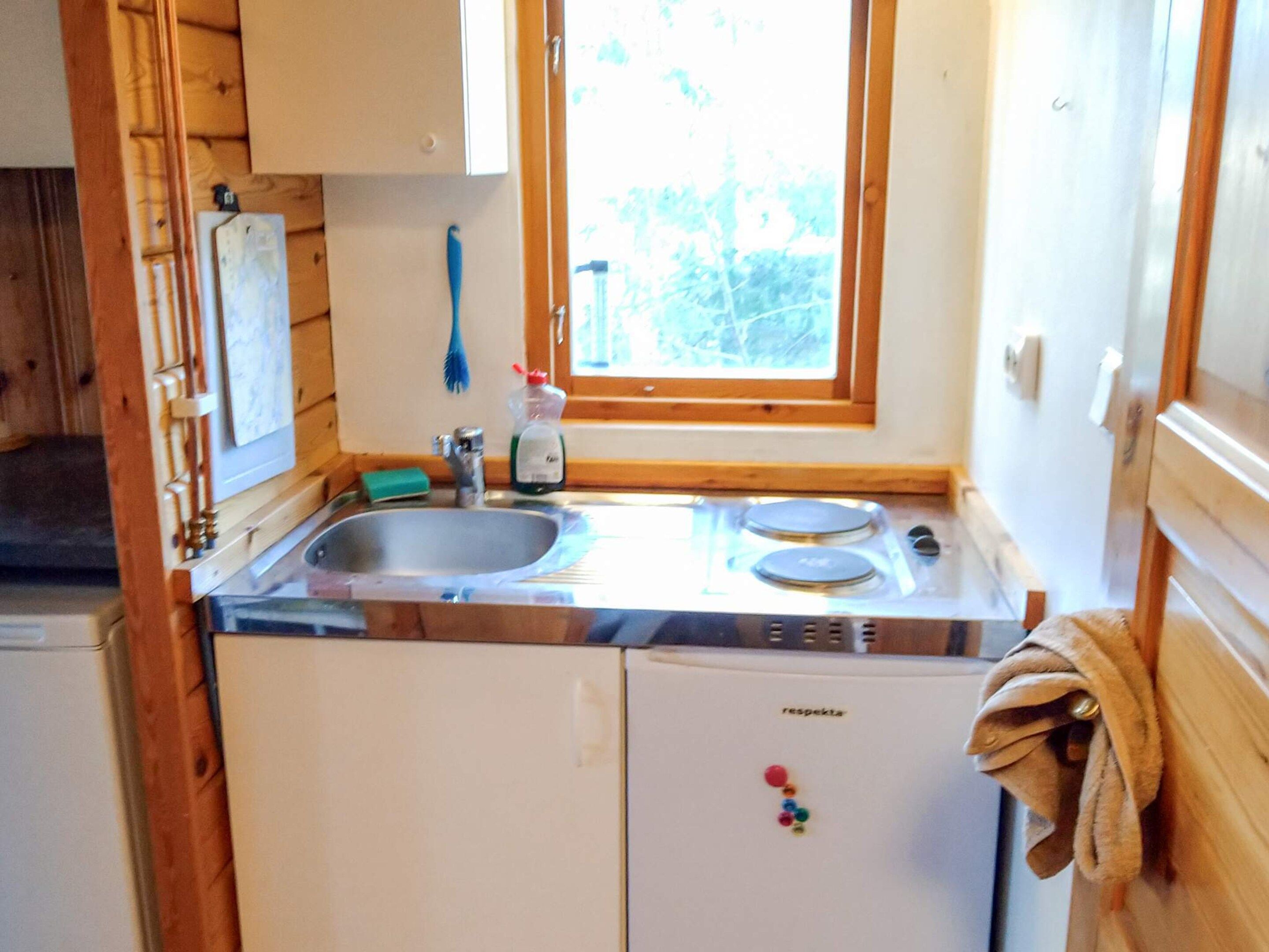 A compact kitchen with a sink, stove, and a window above the sink.
