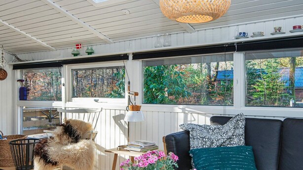 A cozy room with a rocking chair, a sofa with patterned cushions, and a potted plant on a light-colored table. - 4 Star Holiday Home in Ansager (Ansager)