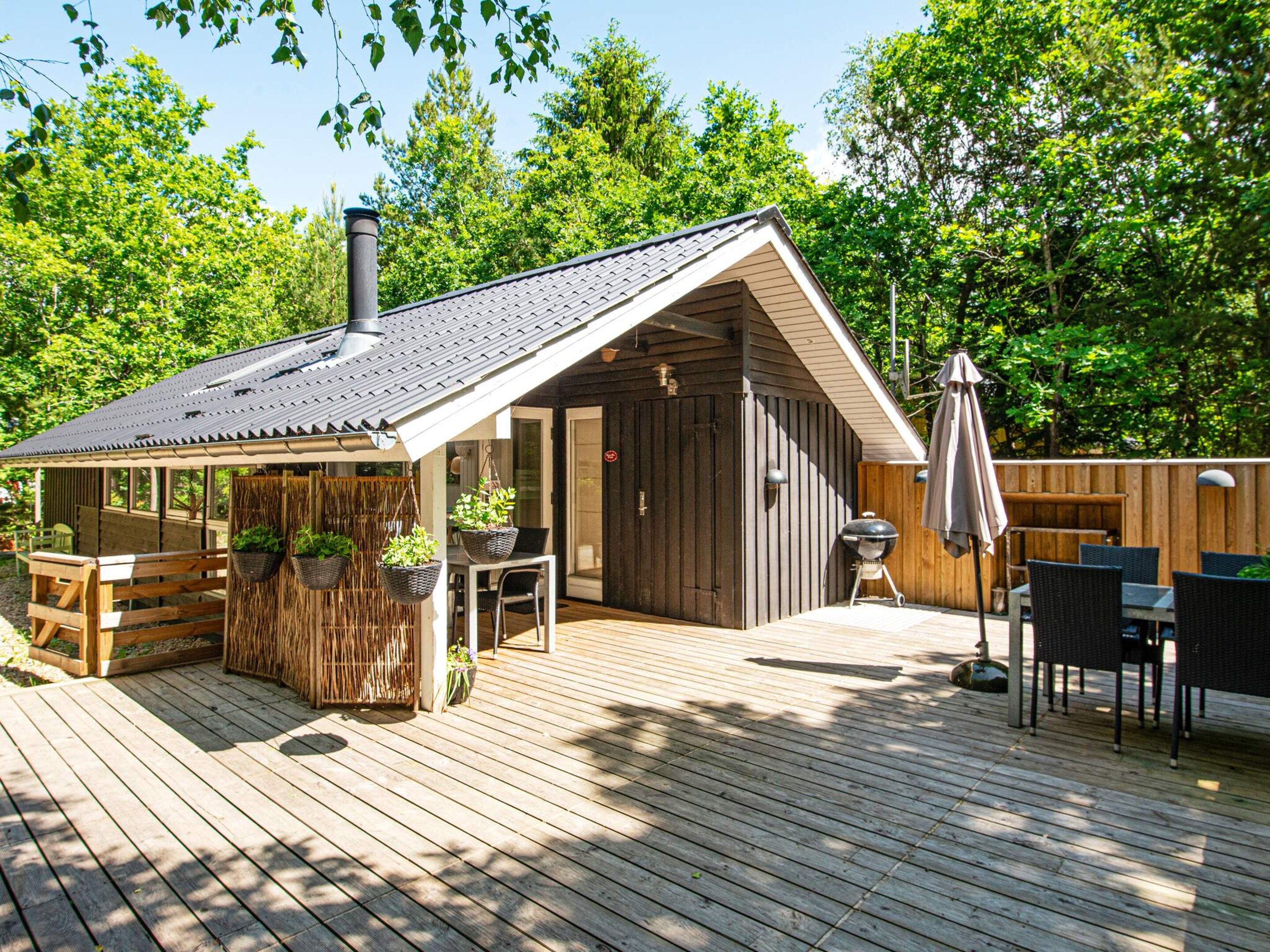 A wooden deck with outdoor seating, a barbecue grill, and hanging planters.