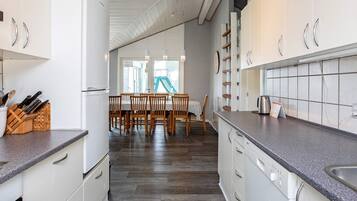 Et moderne køkken med hvide skabe, en granitbordplade og et spiseområde med træstole og et bord.
