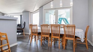 A dining area with a wooden table and chairs, a kitchen area, and a view of a slide. - Spacious Holiday Home in Vestervig near Sea (Vestervig)