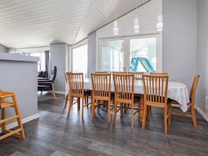 Un coin repas avec une table et des chaises en bois, un espace cuisine et une vue sur un toboggan.