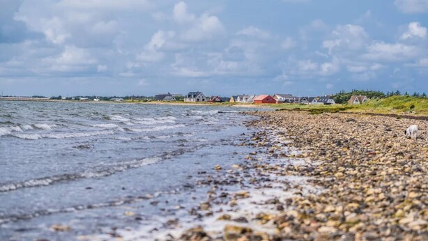A pebbly beach with a row of houses and a body of water. - Spacious Holiday Home in Vestervig near Sea (Vestervig)