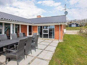 A house with a patio area featuring a table and chairs, a satellite dish, and a brick exterior.