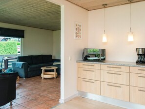 Un espacio habitable compacto con kitchenette, un sofá, una pequeña mesa redonda y vistas a zonas verdes.
