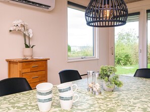 A dining area with a table set for four, a wooden cabinet, a potted plant, and a hanging light fixture. - 4 Person Holiday Home in Borkop (Borkop)