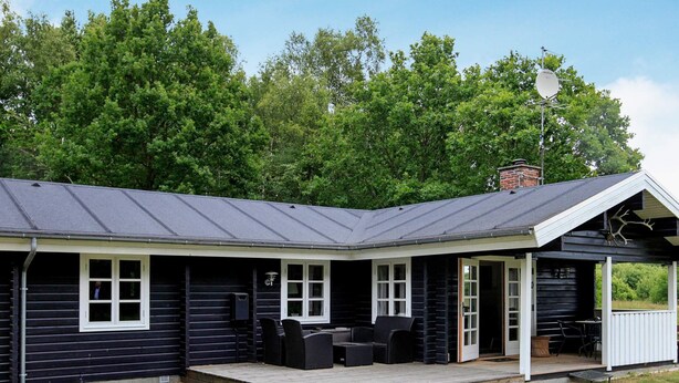 A cabin with a covered porch, a chimney, and a satellite dish.